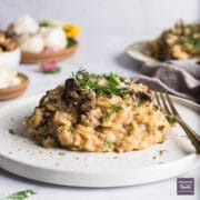 Porcini mushroom risotto on a small plate with fresh dill and parmesan.