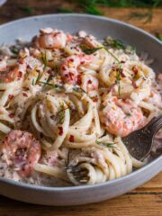 A bowl of linguine in a creamy sauce with salmon and prawns.