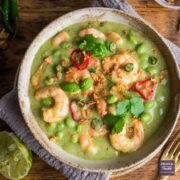 Thai green prawn curry served in a bowl and topped with fresh basil and chillies.