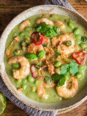 Thai green prawn curry served in a bowl and topped with fresh basil and chillies.