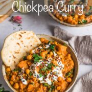 Sweet potato, chickpea & spinach vegetarian curry in a bowl with naan bread and topped with yogurt and coriander.