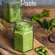 A small jar filled with homemade Thai green curry paste with a spoonful of paste and a chopped up green finger chilli at the side.