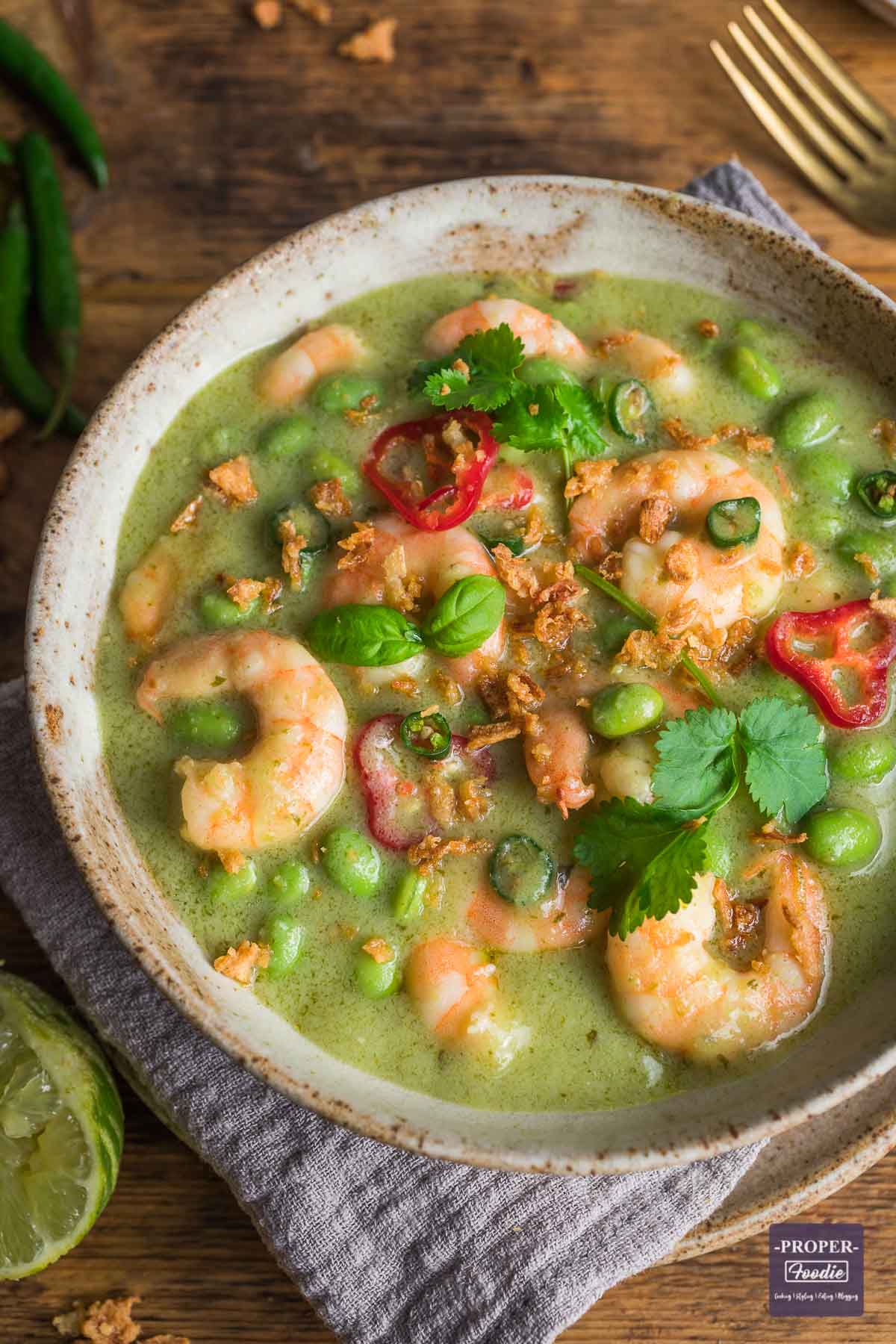 Thai green prawn curry served in a bowl and topped with fresh basil and chillies.