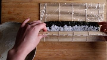 use the bamboo mat to start rolling and folding your maki sushi