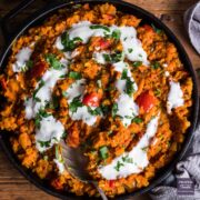 Red lentil dahl in a wide cast iron pan and topped with yogurt and parsley